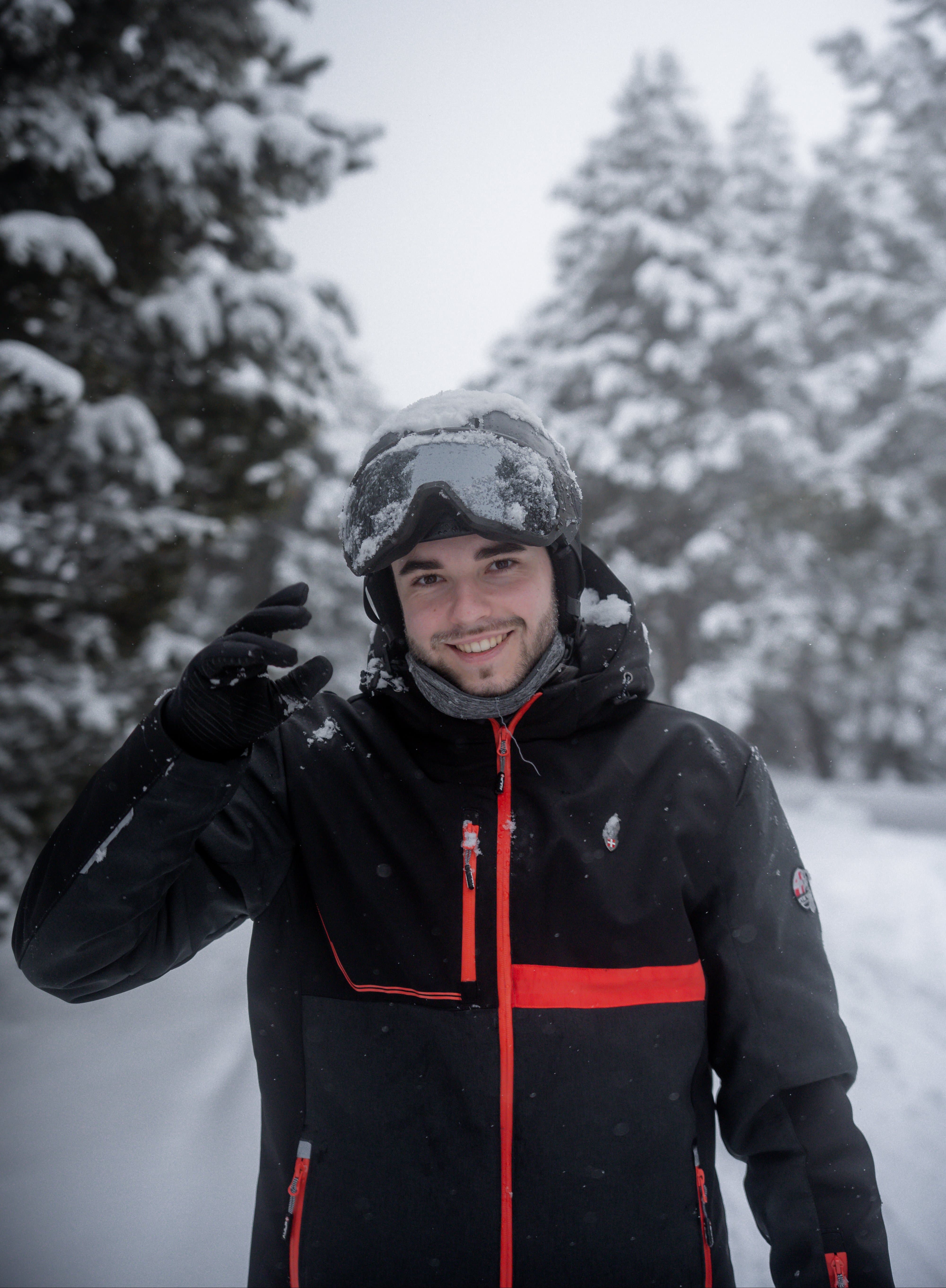 Portrait d’un skieur souriant sous la neige dans un décor de montagne hivernal